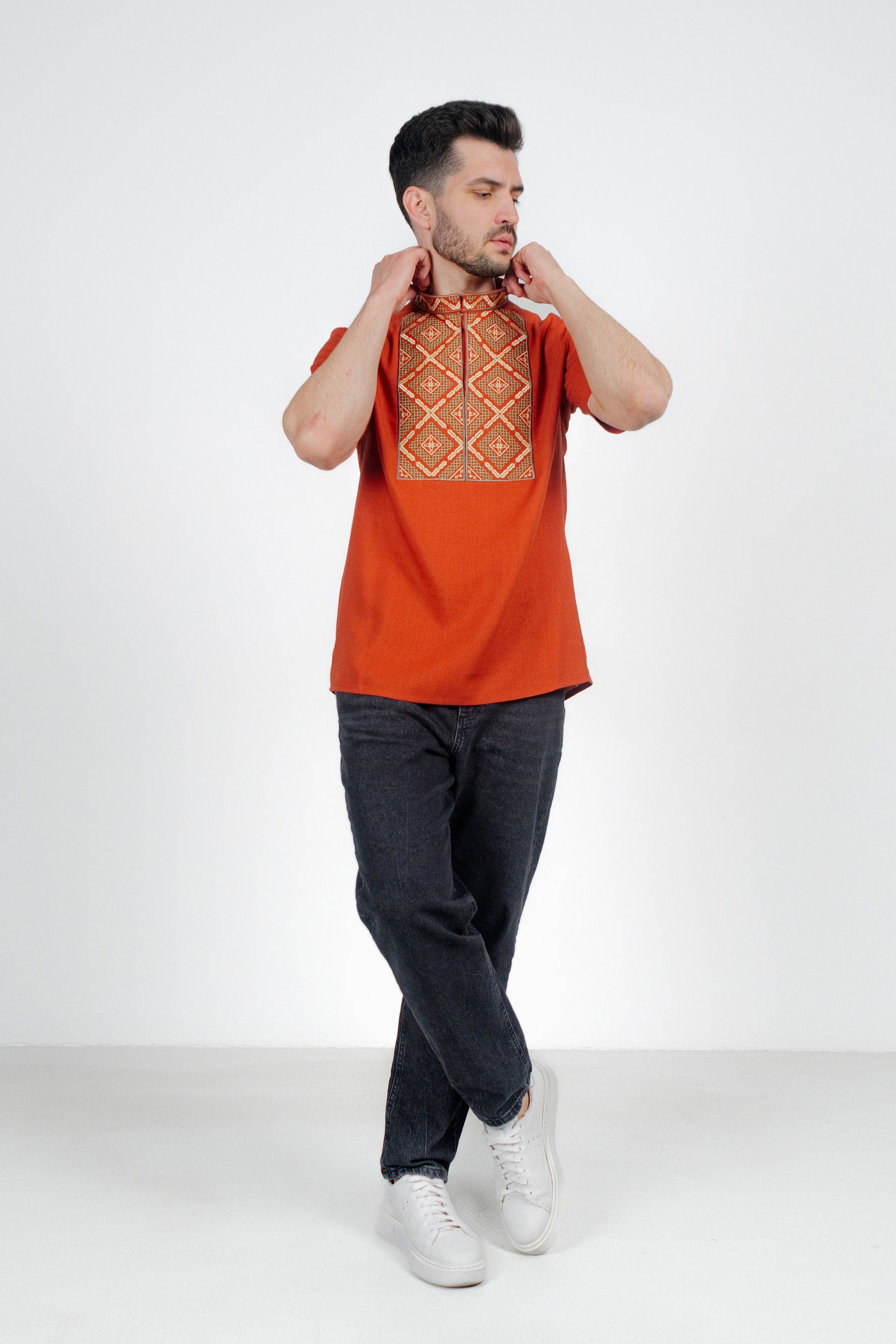 Model wearing men's orange short sleeve Ukrainian embroidered shirt with geometric design, made of linen-cotton blend.