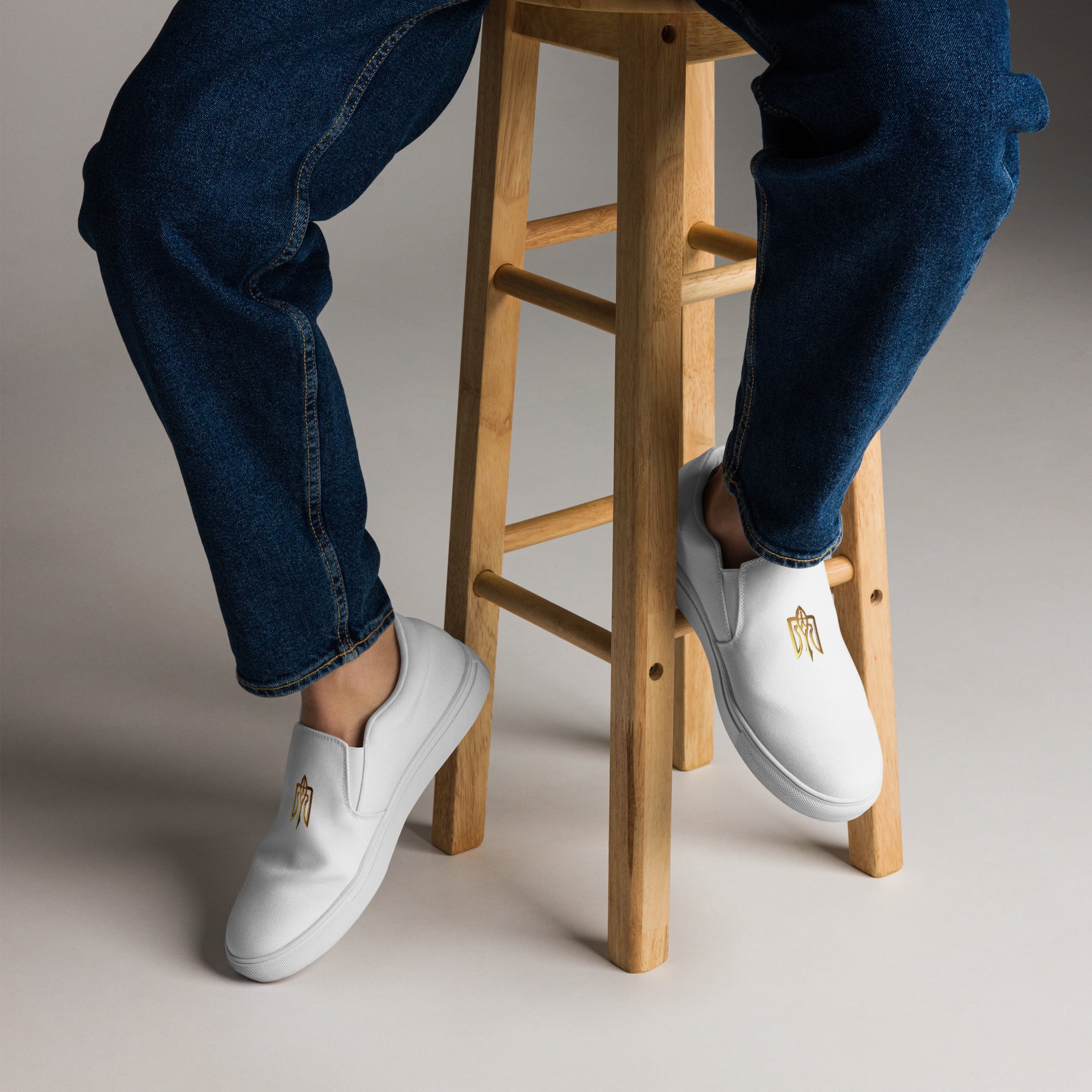 Person wearing Gold Ukrainian Trizub Slip-On Canvas Shoes sitting on a wooden stool, showcasing style and comfort.