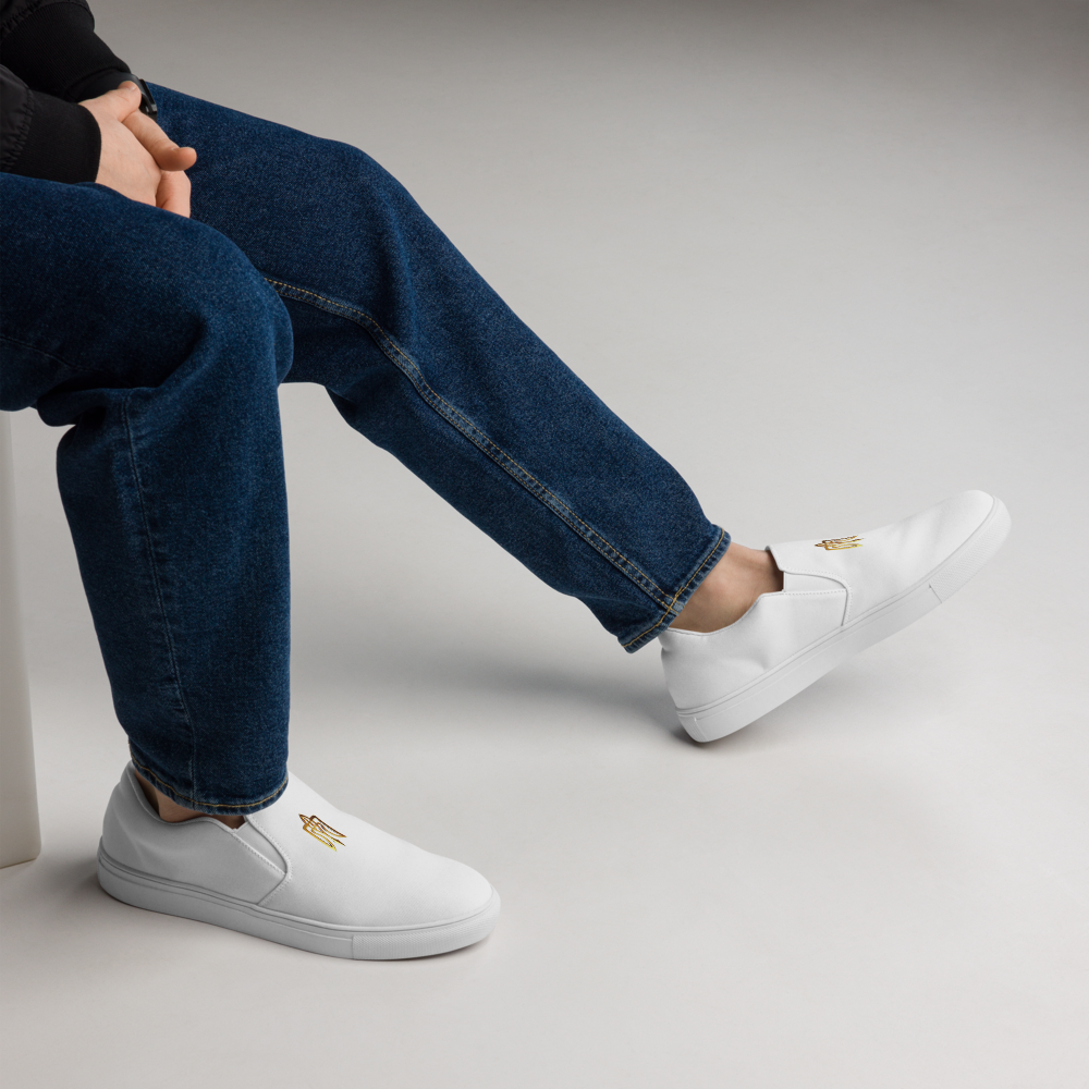 White slip-on canvas shoes with gold Ukrainian Trizub design shown worn with jeans, highlighting style and comfort.