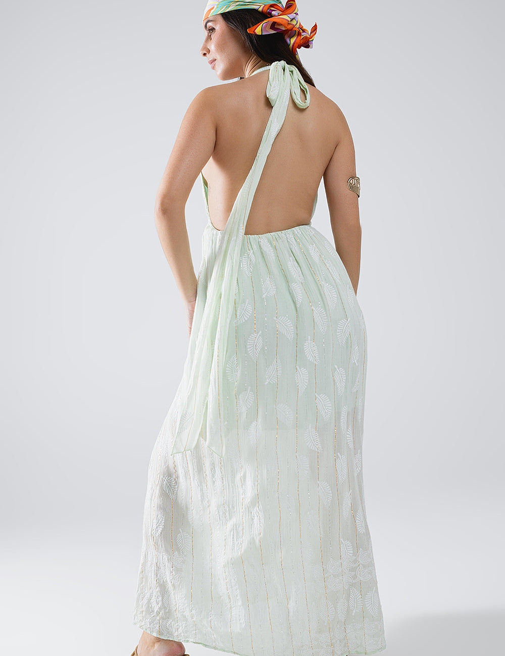 Back view of Mintara Leaf-Lurex Halter Dress in mint-green leaf print, showing halter ties and mid-calf skirt. Perfect for boho style.