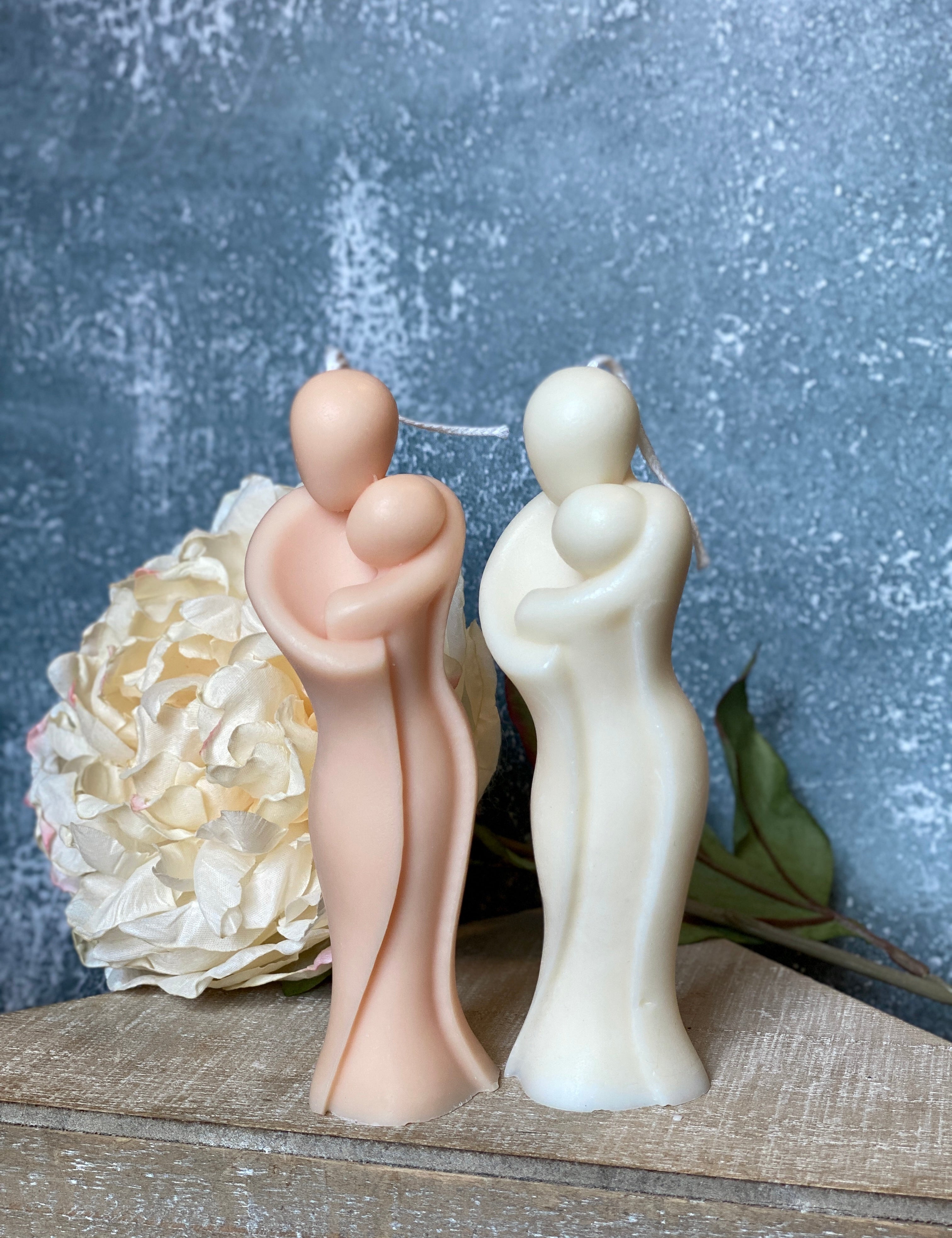 Sculptural Mamelle Candle in organic soy wax, symbolizing maternal warmth and protection, set against a textured backdrop with floral accent.