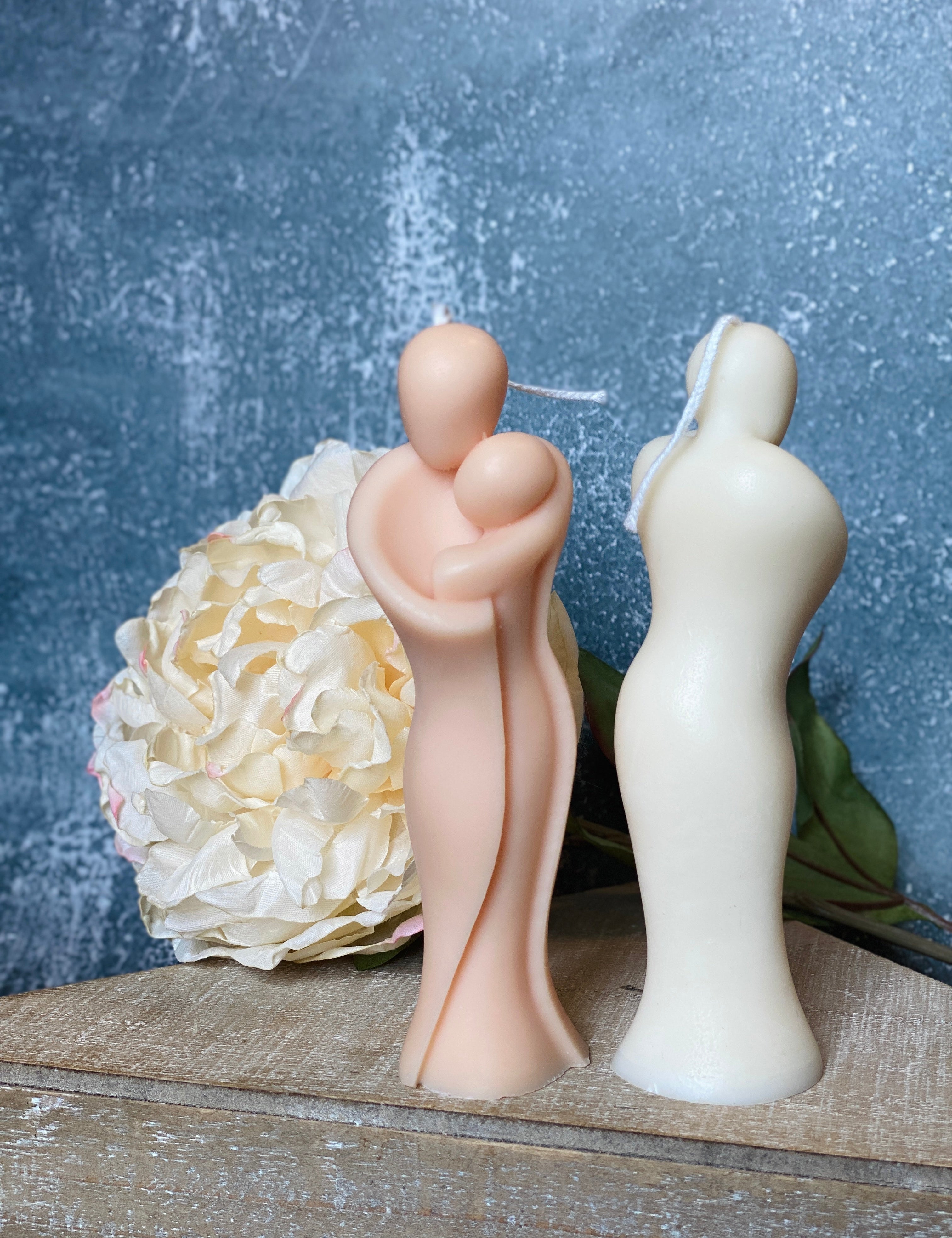 Sculptural candle of maternal warmth in organic soy wax with floral backdrop, symbolizing protection and love.