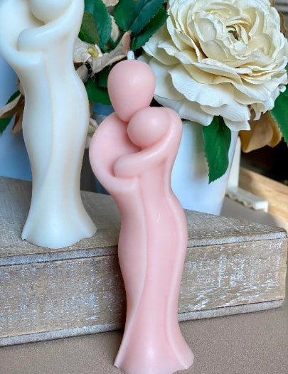 Sculptural candle in the shape of an embracing couple, made from organic soy wax, symbolizing maternal warmth and love.