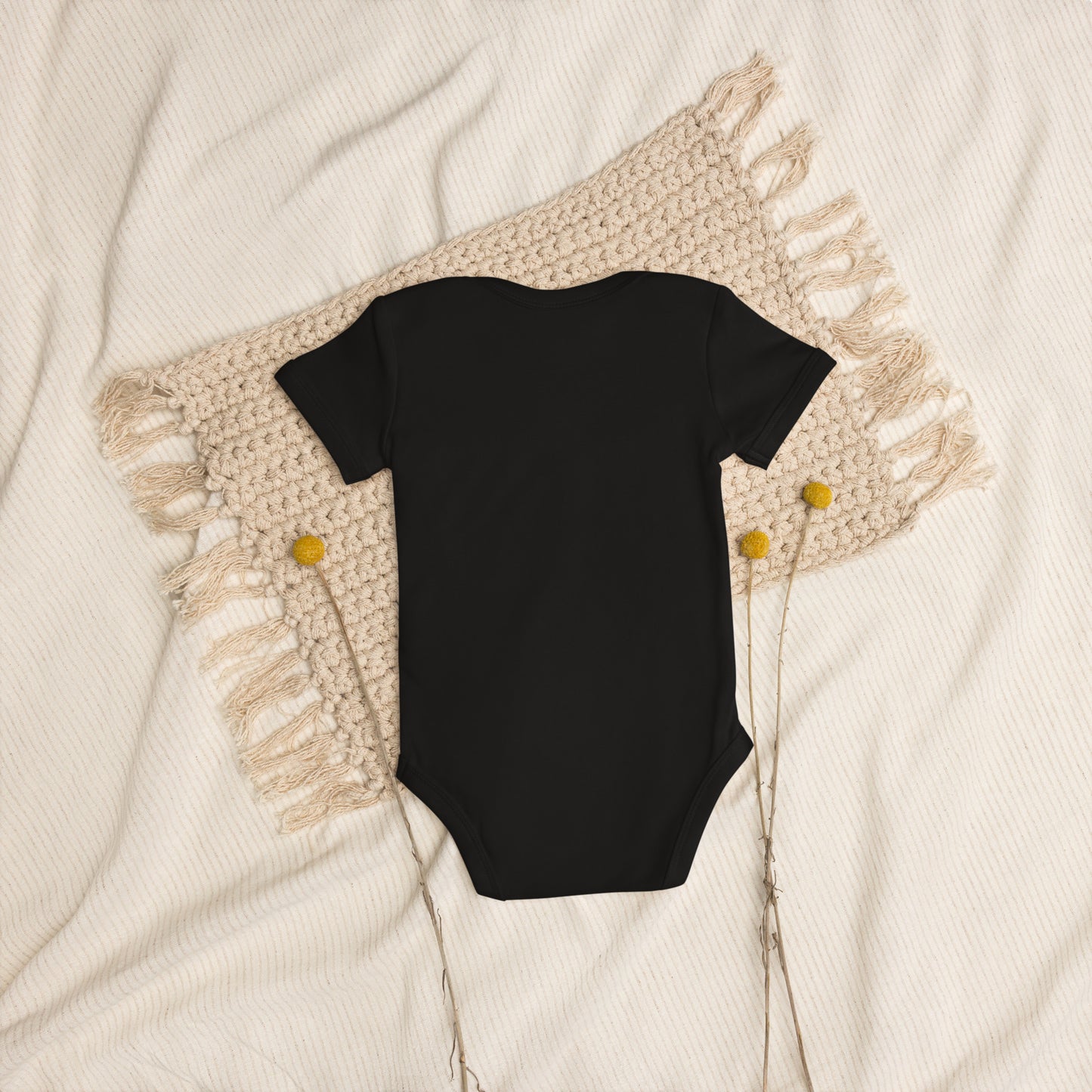 Organic cotton baby bodysuit with Ukranian Tryzub logo on woven blanket background.