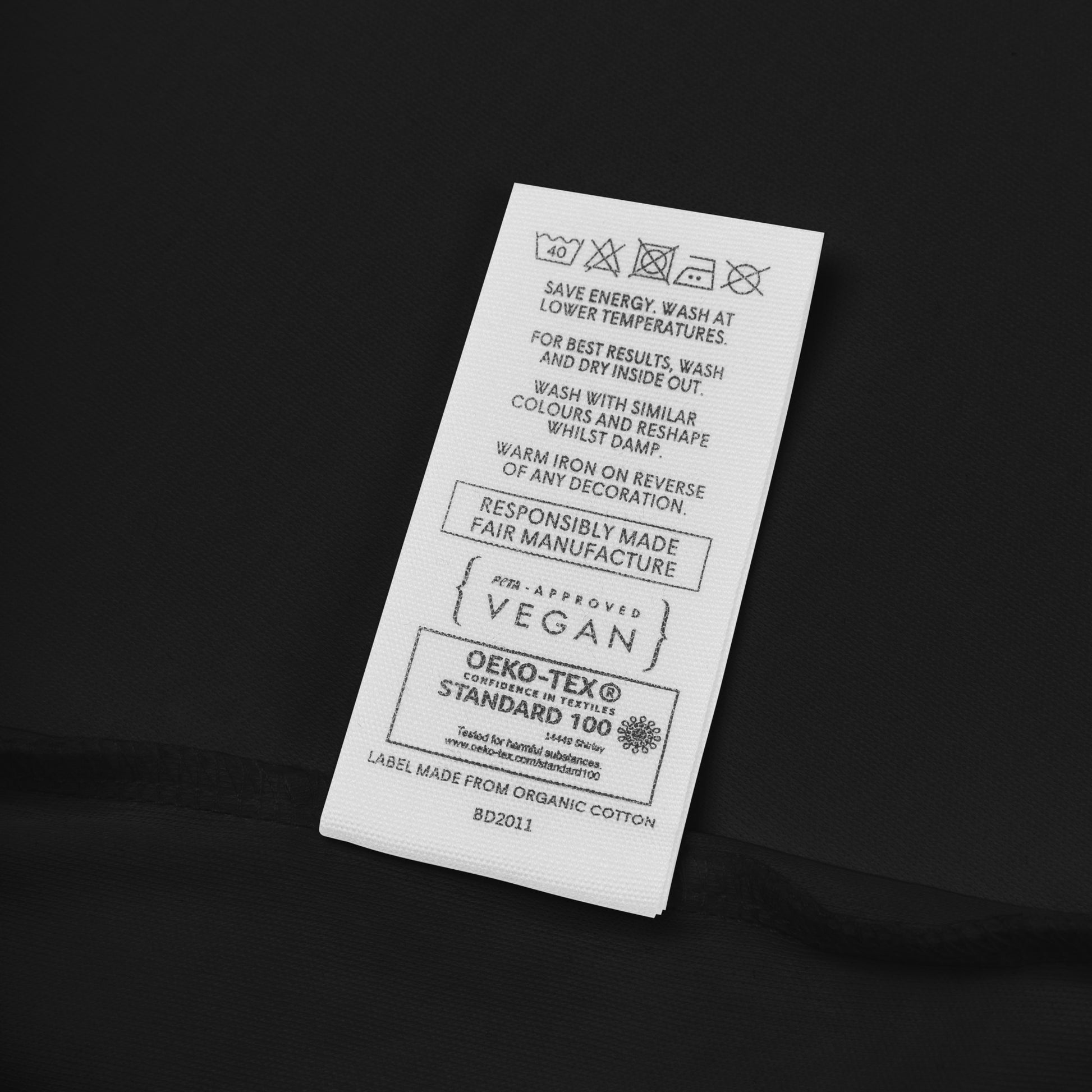 Clothing label with washing instructions, vegan certification, and OEKO-TEX Standard 100 on organic cotton fabric.