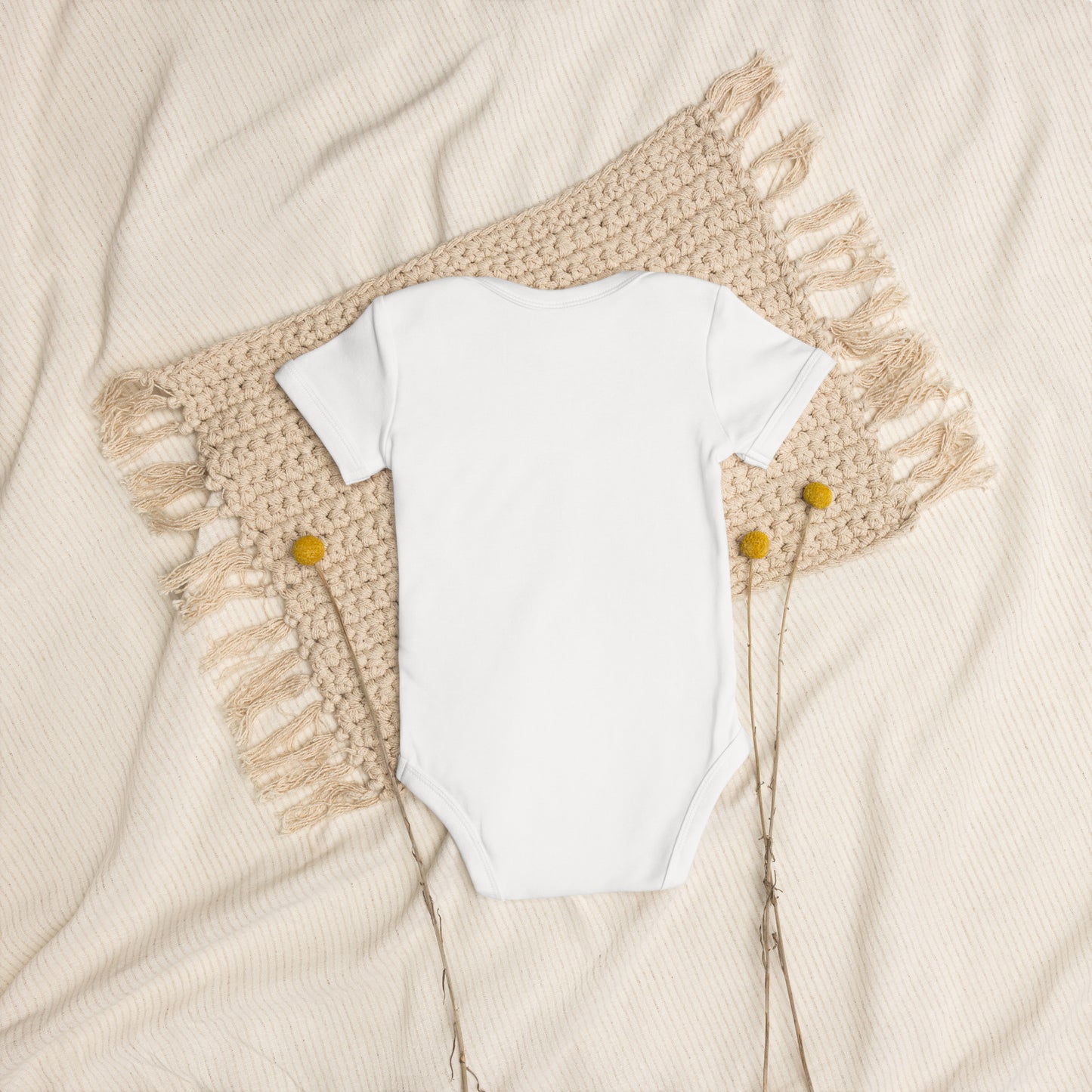 Organic cotton baby bodysuit with Ukrainian Tryzub logo displayed on a textured beige background.