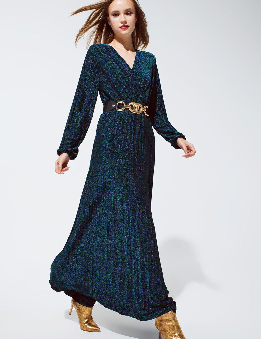 Model wearing Midnight Spark Lurex Gown with deep V-neckline, long sleeves, and gold belt, ideal for evening events.