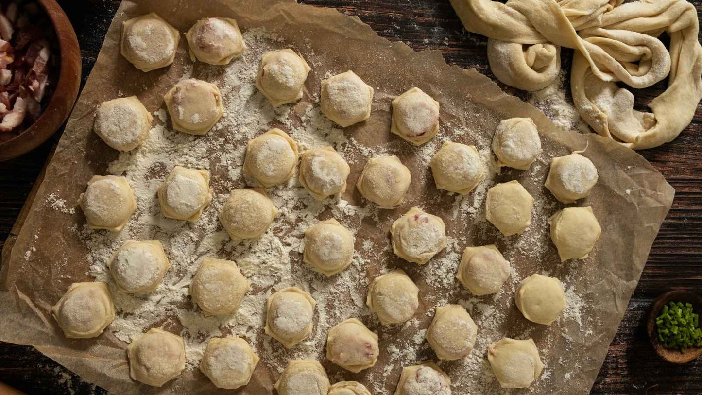 Homemade Ukrainian Pelmeni dumplings on parchment, ready to cook. Traditional frozen dumplings with various meat fillings.