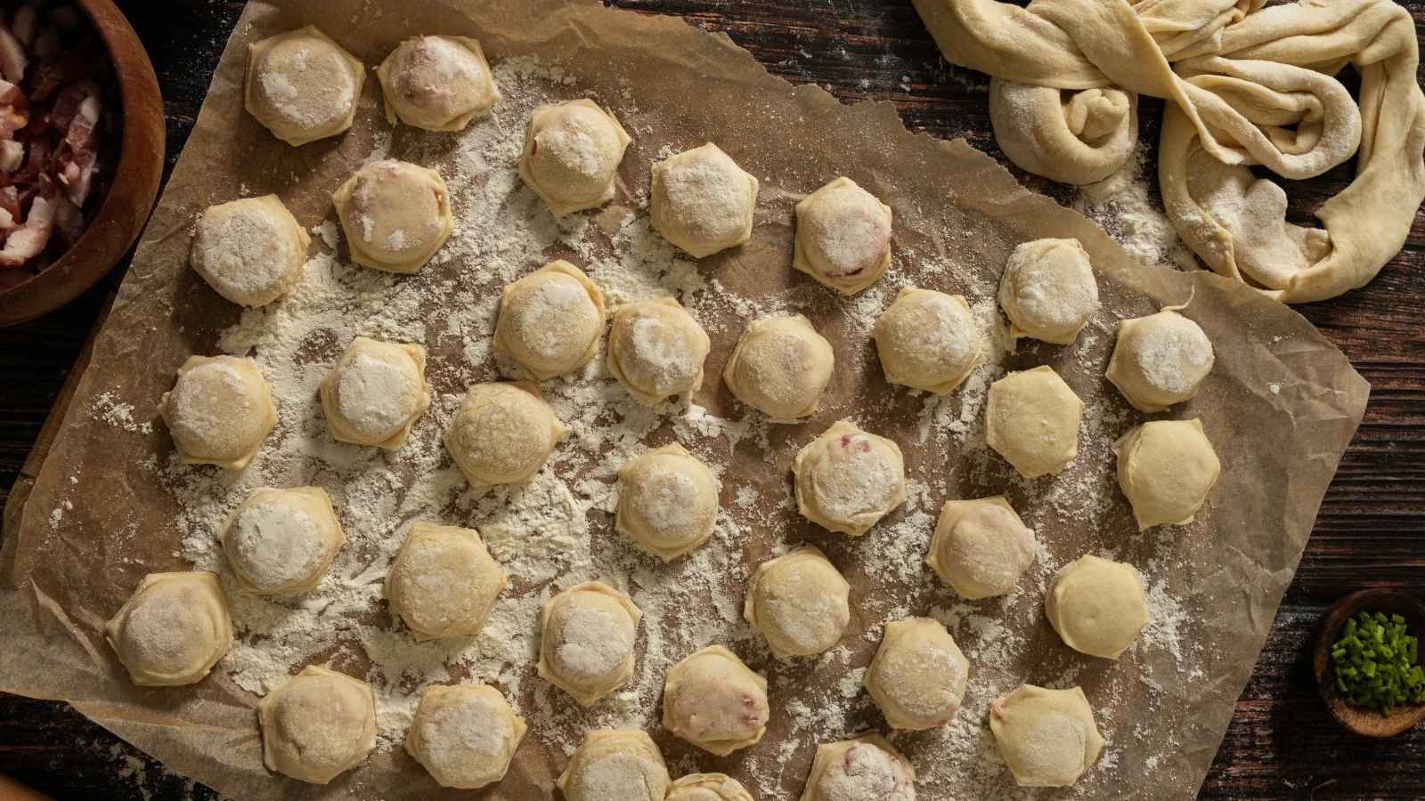 Homemade Ukrainian Pelmeni dumplings on parchment, ready to cook. Traditional frozen dumplings with various meat fillings.