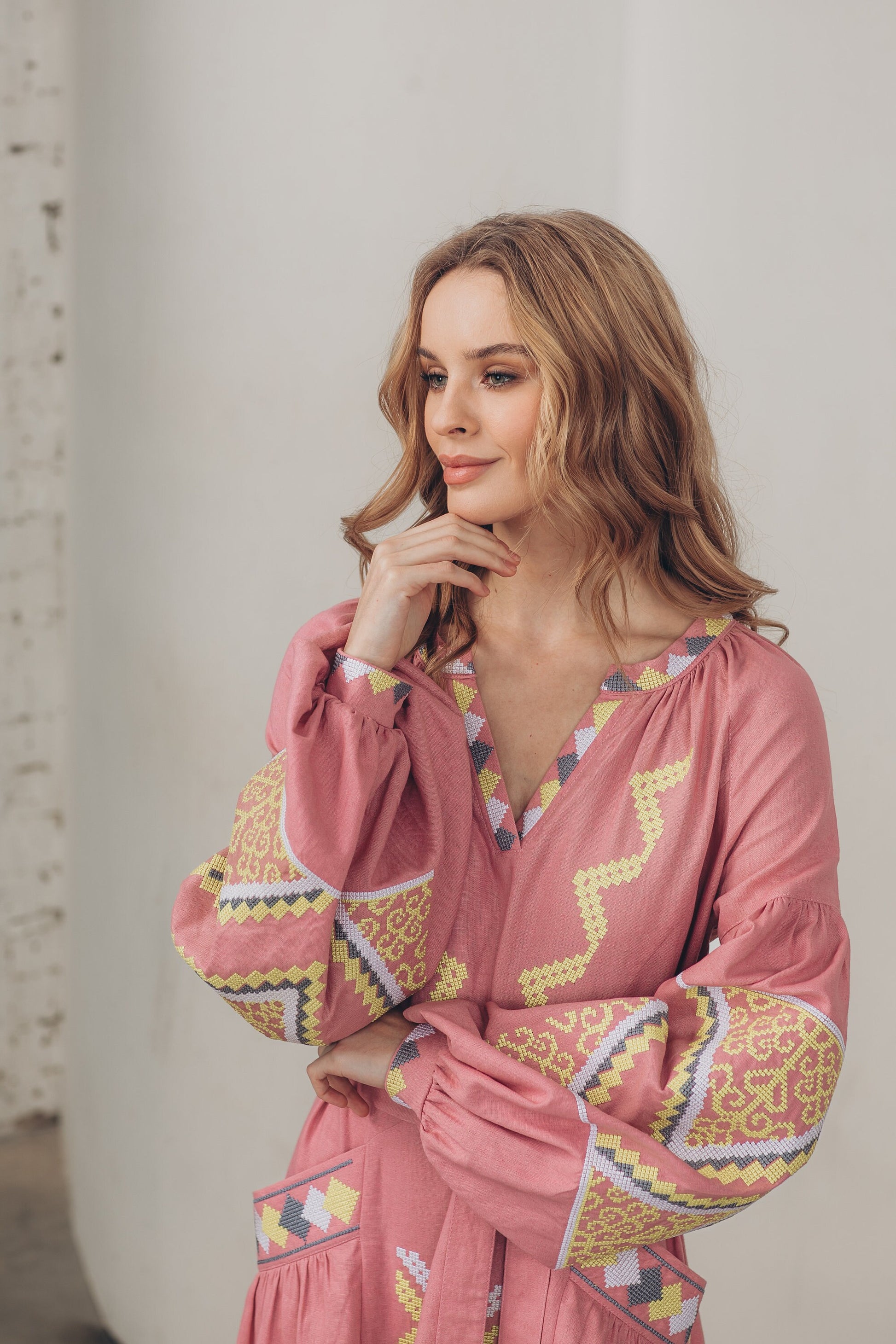 Woman wearing pink linen embroidered Vyshyvanka dress, Ukrainian folk style with belt and pockets, boho fashion.
