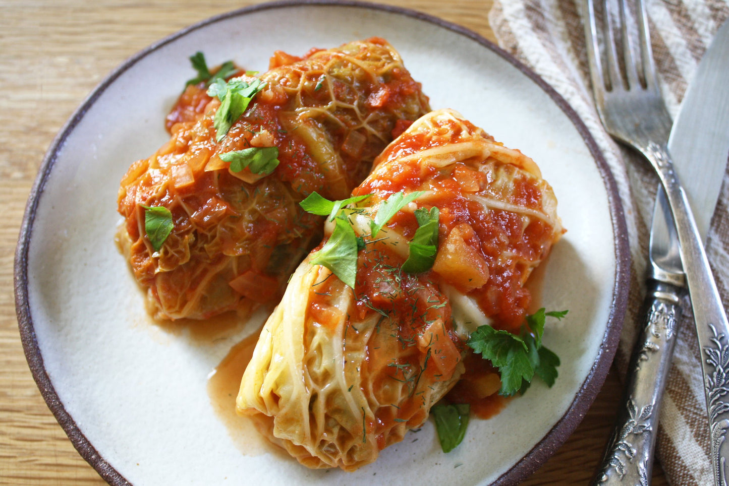 Homemade Ukrainian holubtsi stuffed cabbage rolls with rice and meat on a plate, garnished with fresh herbs.