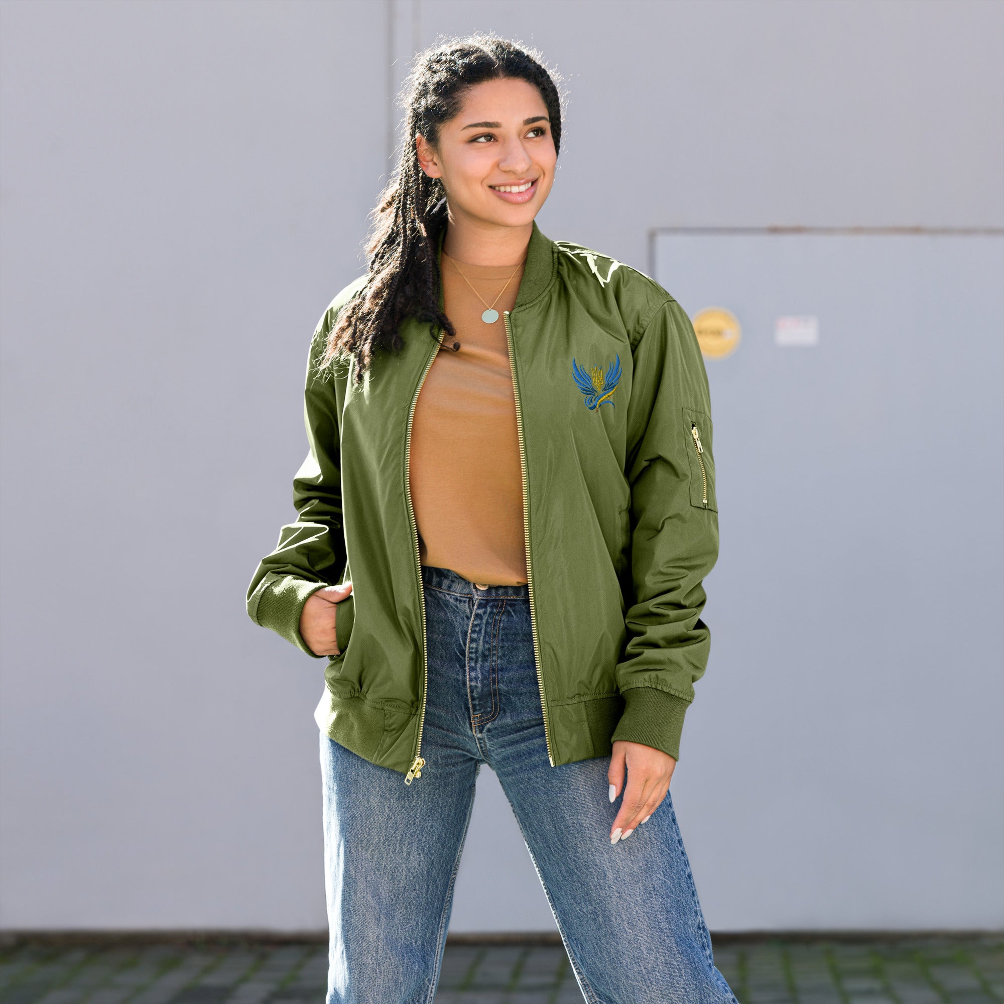 Model wearing Ukrainian premium recycled bomber jacket in green, showcasing eco-friendly fashion and Trizub Collection design.