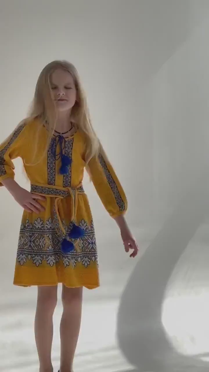 Girl wearing a golden-yellow Ukrainian knitted dress with blue and white embroidery, perfect for traditional and festive occasions.