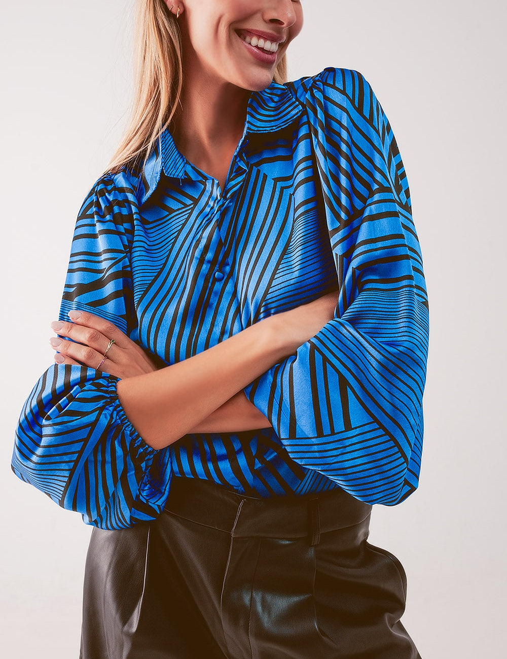 Model wearing blue-toned striped puff sleeve blouse with wide collar and ruched sleeves, styled with black pants.