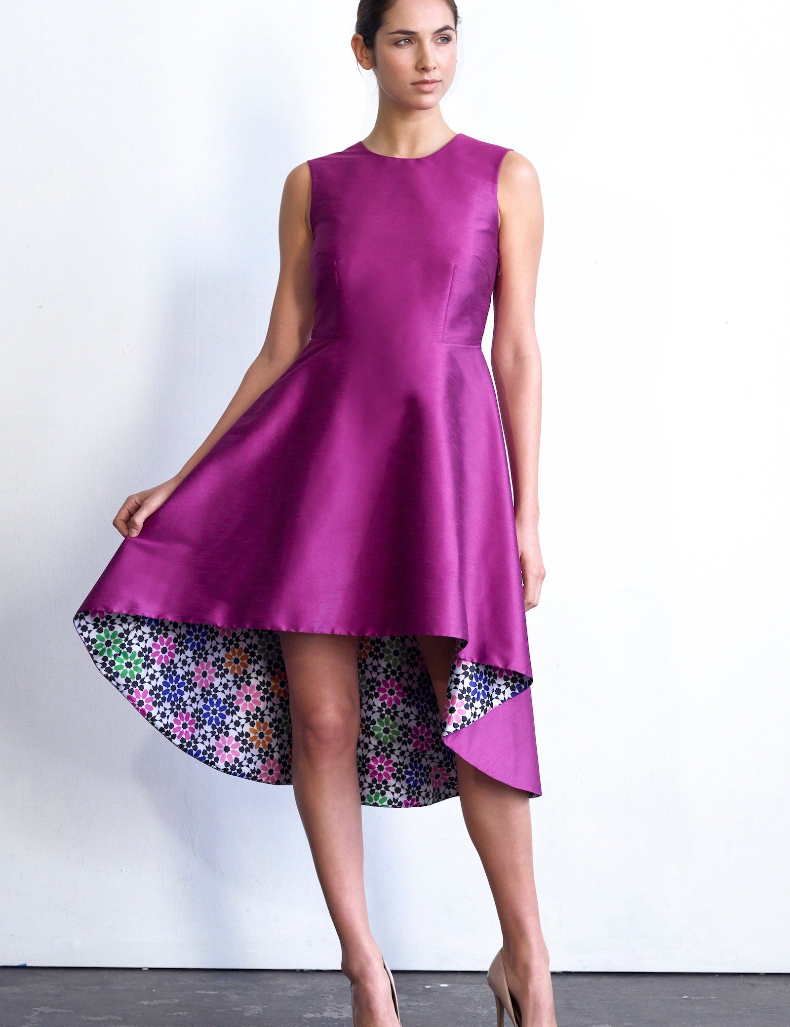 Woman wearing Eliora Open-Back Pink Hi-Lo Dress with multicolor lining, showcasing structured poly dupioni fabric and elegant silhouette.