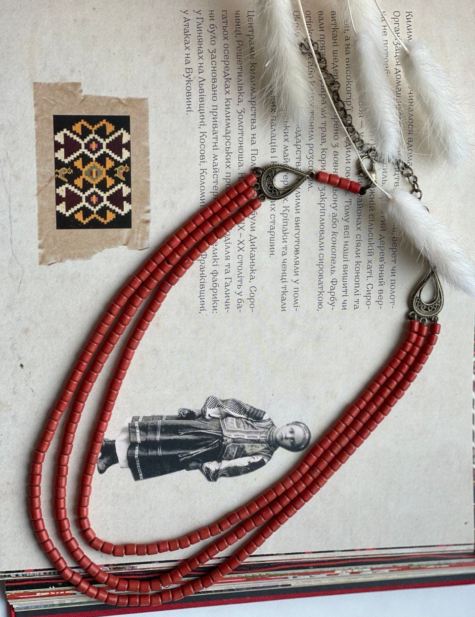 Red ceramic beaded necklace in Hutsul style, showcasing Ukrainian ethnic craftsmanship, laid on a traditional artistic background.