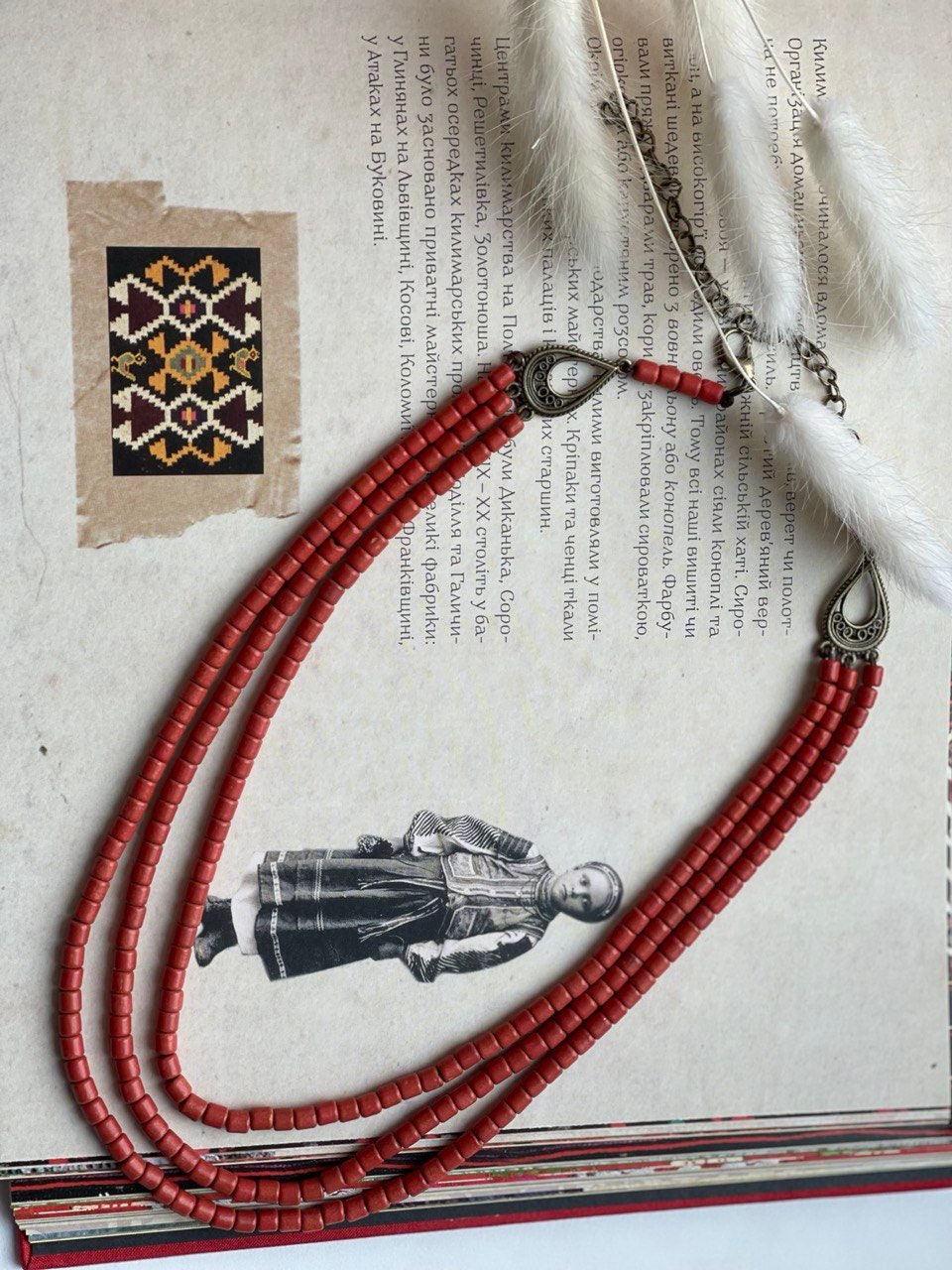 Red ceramic beaded necklace in Hutsul style, showcasing Ukrainian ethnic craftsmanship, laid on a traditional artistic background.