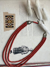 Handmade red ceramic beaded necklace, Hutsul style, inspired by Ukrainian ethnic jewelry, set on traditional background.