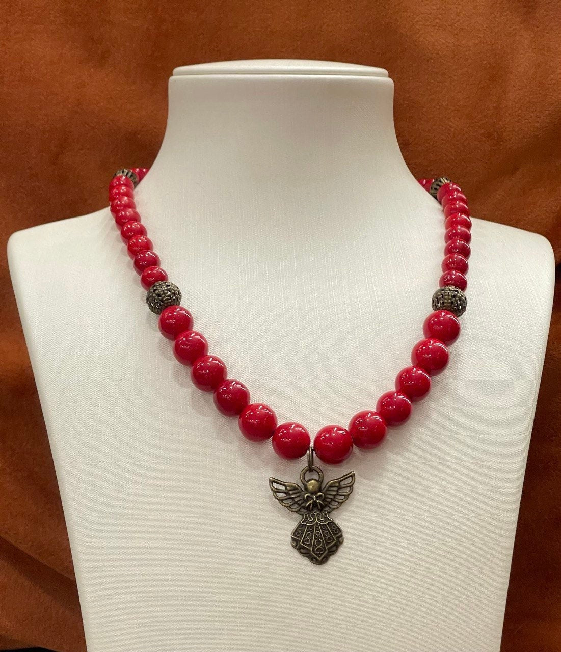 Hutsul handmade red coral bead necklace with angel pendant on white display, Ukrainian ethnic jewelry gift for her.