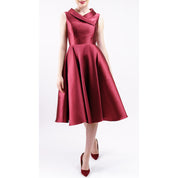 Woman wearing Leonelle Mikado Asymmetric Collar Dress in pearlescent fabric, showcasing vintage-inspired elegance and modern utility.