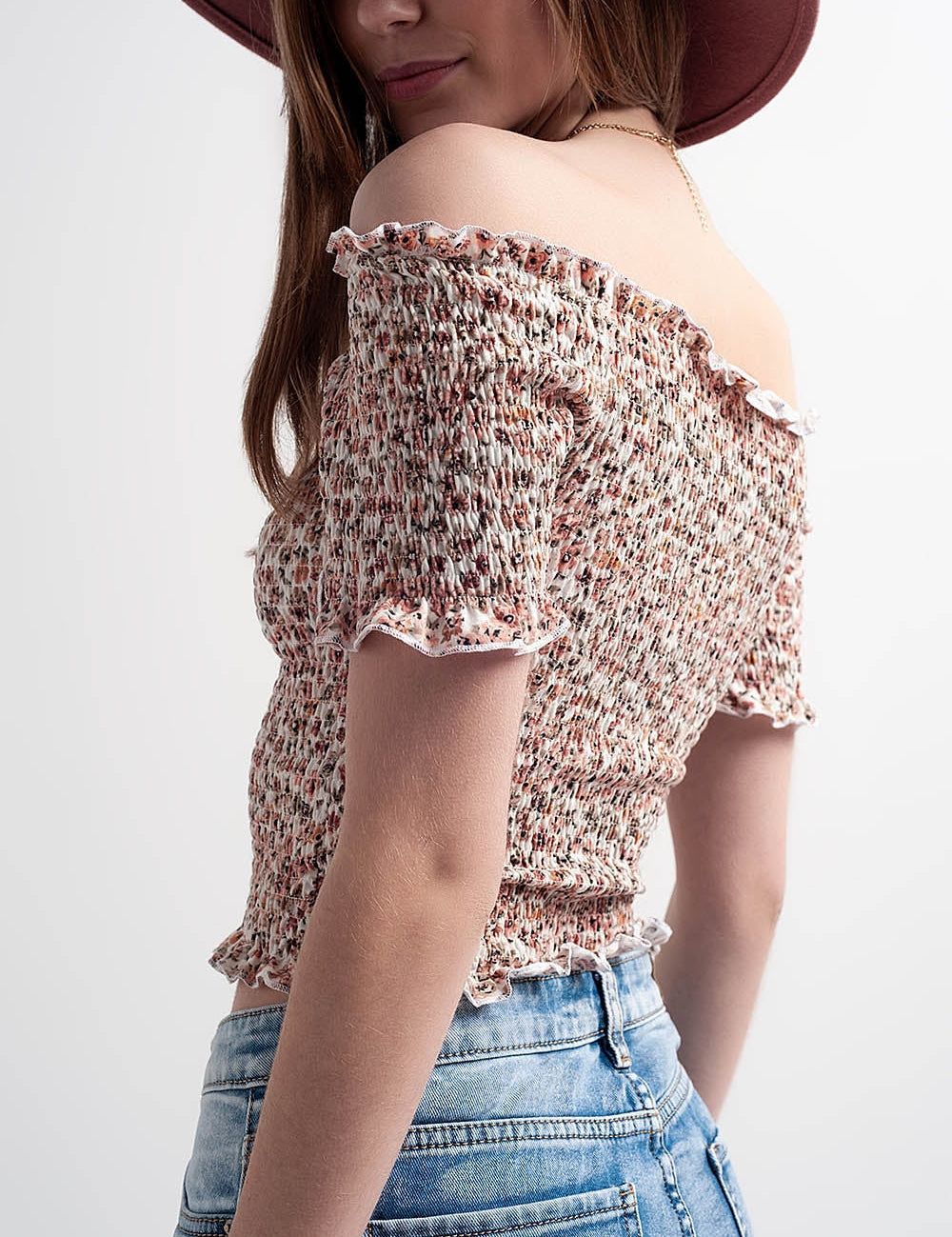 Woman wearing Briselle Bardot Floral Top, shoulder view, with ditsy floral print and romantic Bardot neckline, paired with denim jeans.