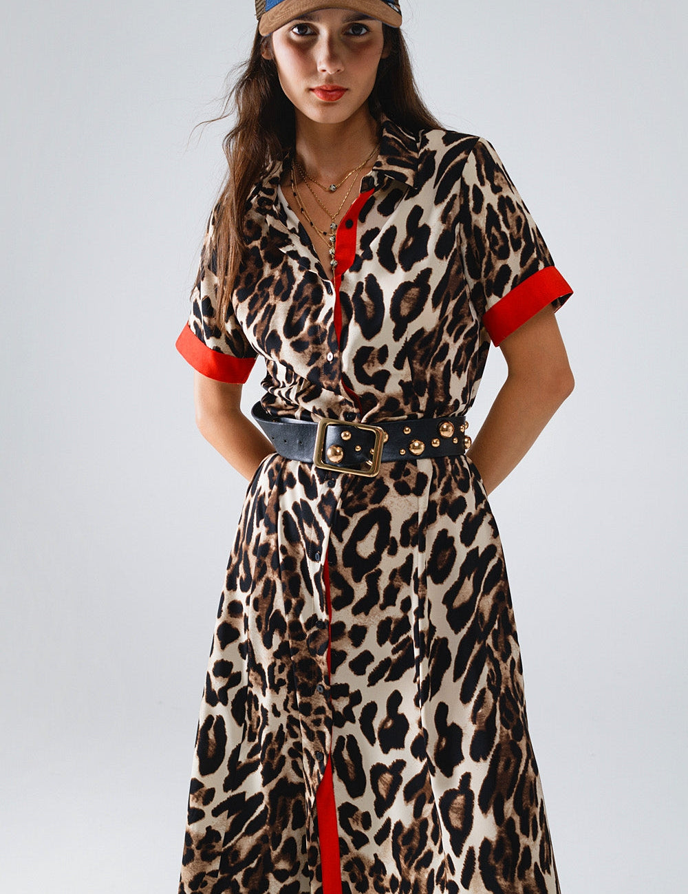 Woman wearing Savanna Red-Trim Leopard Maxi Dress with red collar and short sleeves, styled with a studded belt and hat.