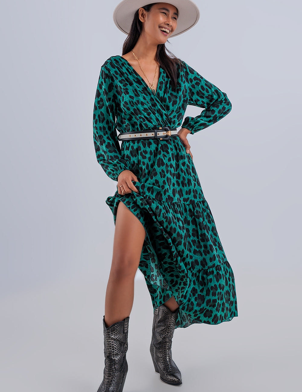 Savanna Tiered Wrap Maxi Dress in vibrant green animal print, featuring V-neck and long sleeves, modeled with a brimmed hat and boots.