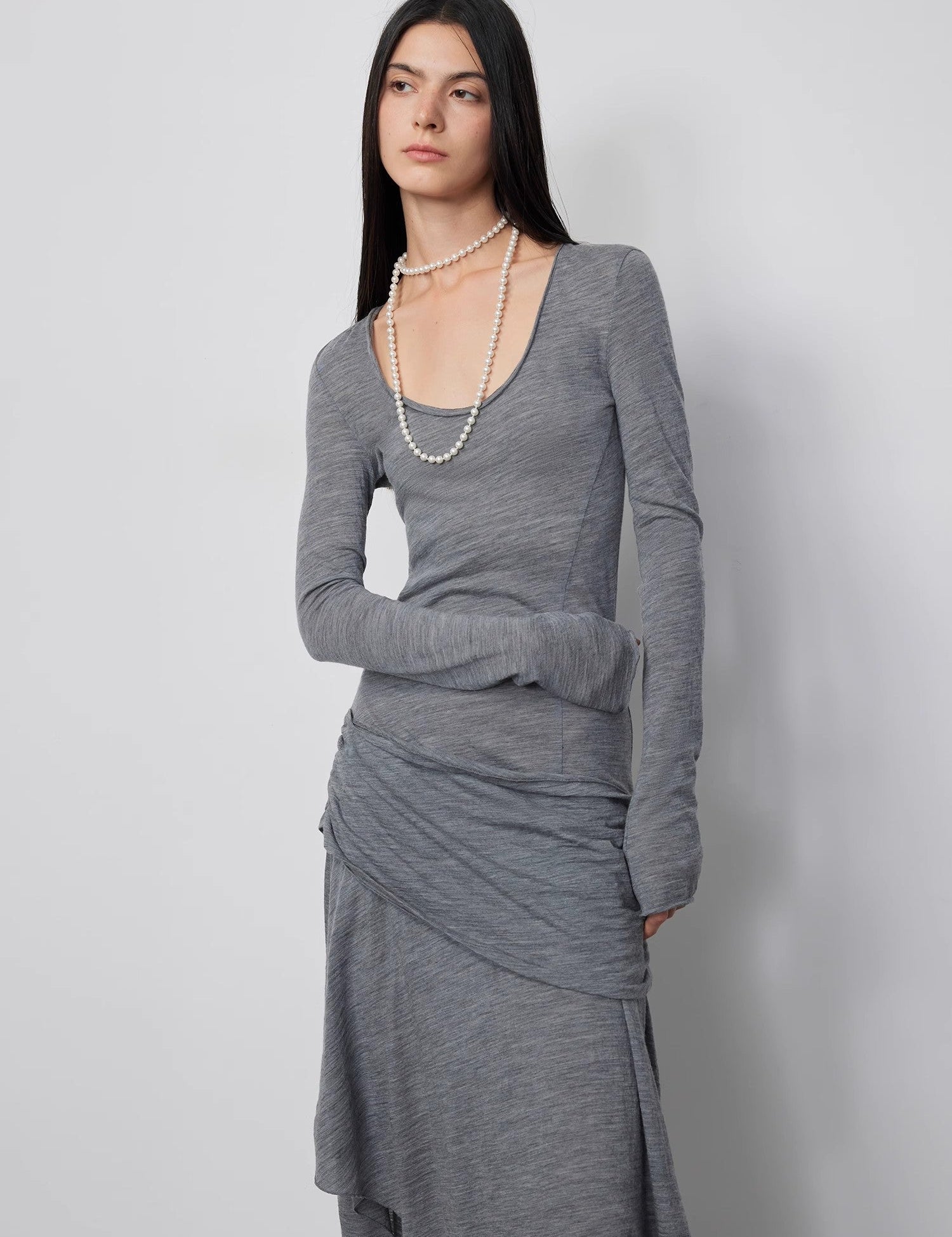 Model wearing Serelis Merino Wool Drape Dress in gray with U-neck and asymmetrical hem.