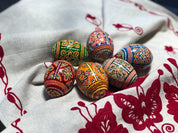 Set of 6 hand-painted Ukrainian pysanky Easter eggs with intricate folk designs on a decorative cloth.