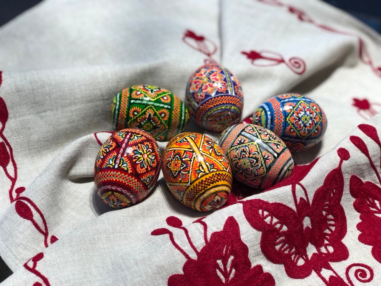 Set of 6 hand-painted Ukrainian pysanky Easter eggs with intricate folk designs on a decorative cloth.