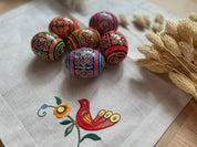 Set of 6 hand-painted Ukrainian Easter eggs with pysanky designs on a cloth, perfect for decoration.