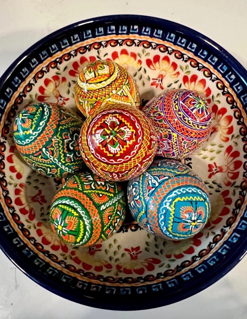 Set of 6 hand-painted wooden eggs in a ceramic bowl, showcasing colorful traditional Ukrainian Pysanky designs.