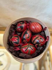 Set of 6 traditional Ukrainian Pysanky eggs, hand-painted in red and black with folk motifs, displayed in a decorative box.