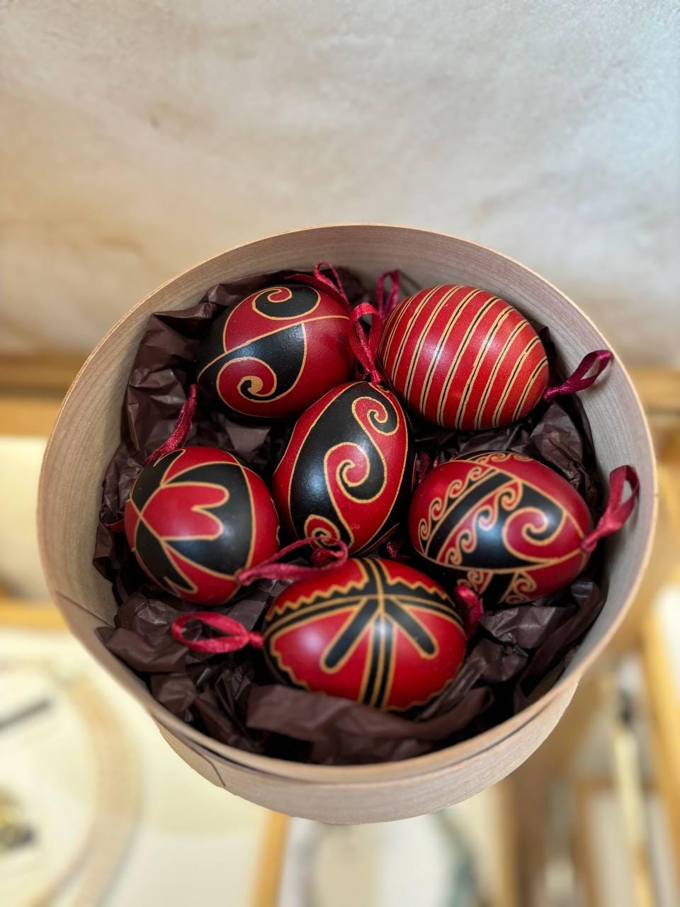 Set of 6 handmade Ukrainian Pysanky eggs in a box, decorated with red and black folk art motifs, traditional Easter gift.