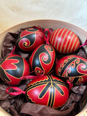 Set of 6 hand-painted Ukrainian Pysanky eggs in a basket, featuring traditional folk art designs and vibrant red and black colors.