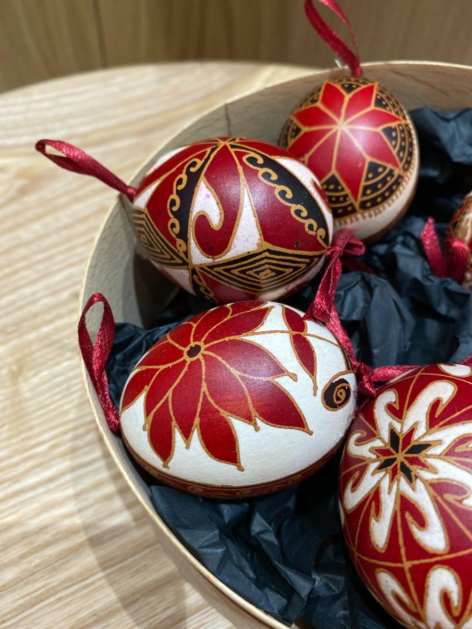Set of handmade Ukrainian Pysanky eggs with red and gold traditional designs in a box, perfect for Easter or Christmas gifts.