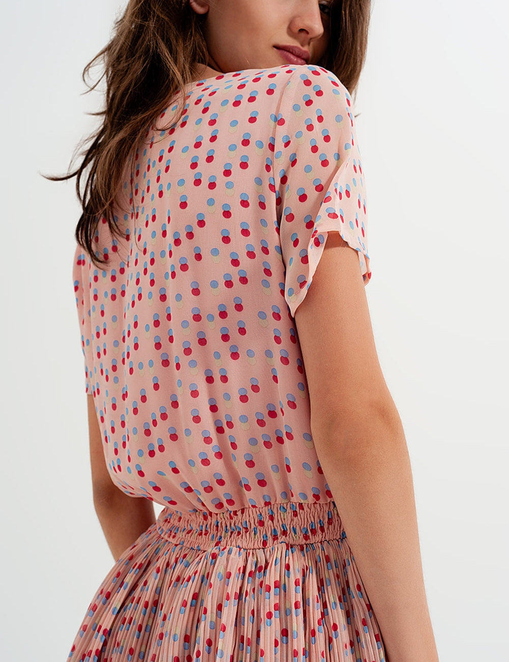 Woman wearing Dot Whimsy Mini Dress with polka-dot print, featuring a shirred bodice and peplum waist, perfect for casual summer style.