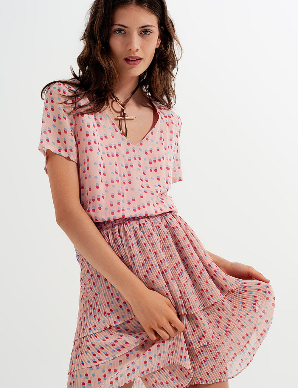 Woman wearing Dot Whimsy Mini Dress with polka dots, featuring a V-neckline, shirred bodice, and peplum waist, perfect for summer.