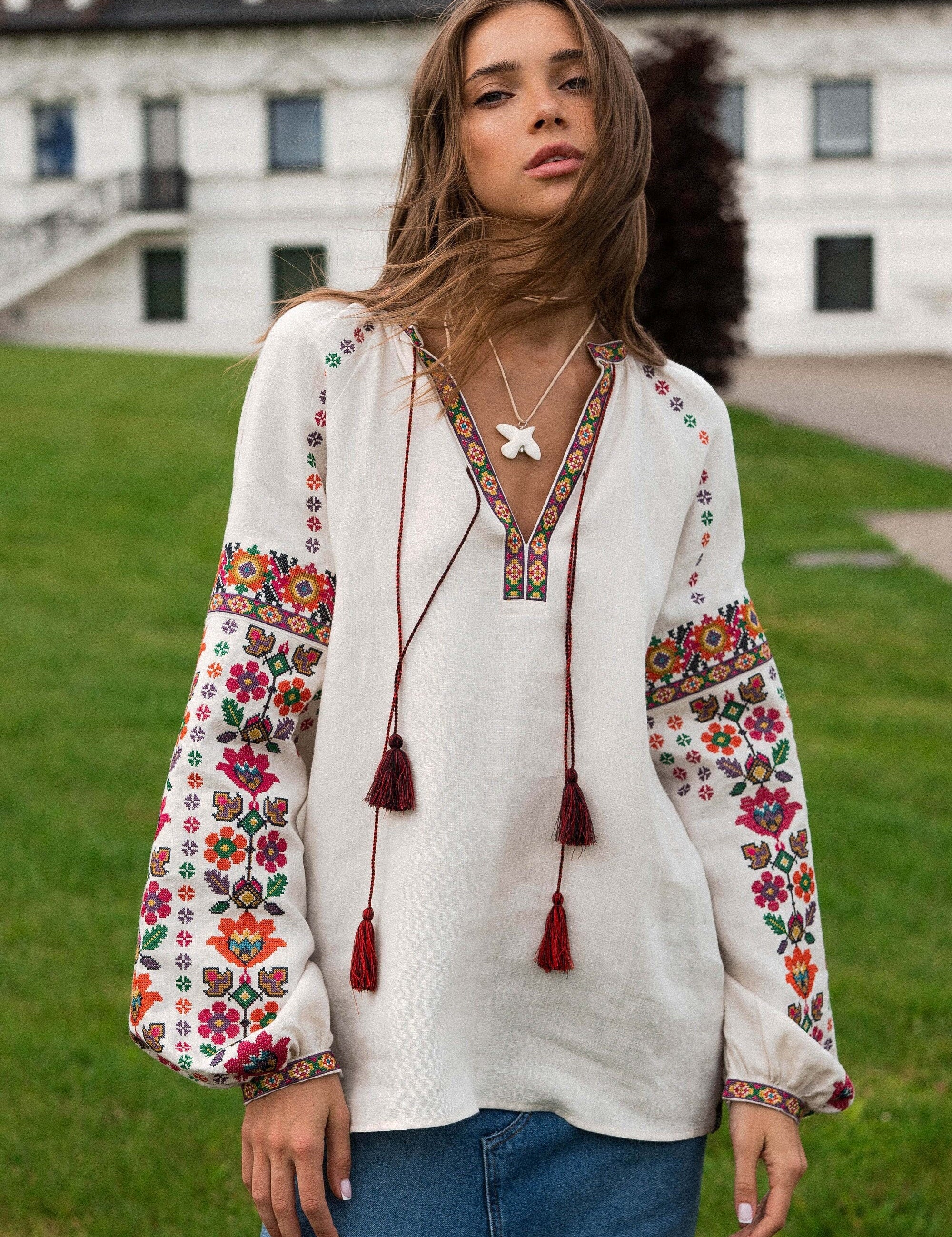 Woman wearing embroidered bohemian blouse outdoors on a grassy field