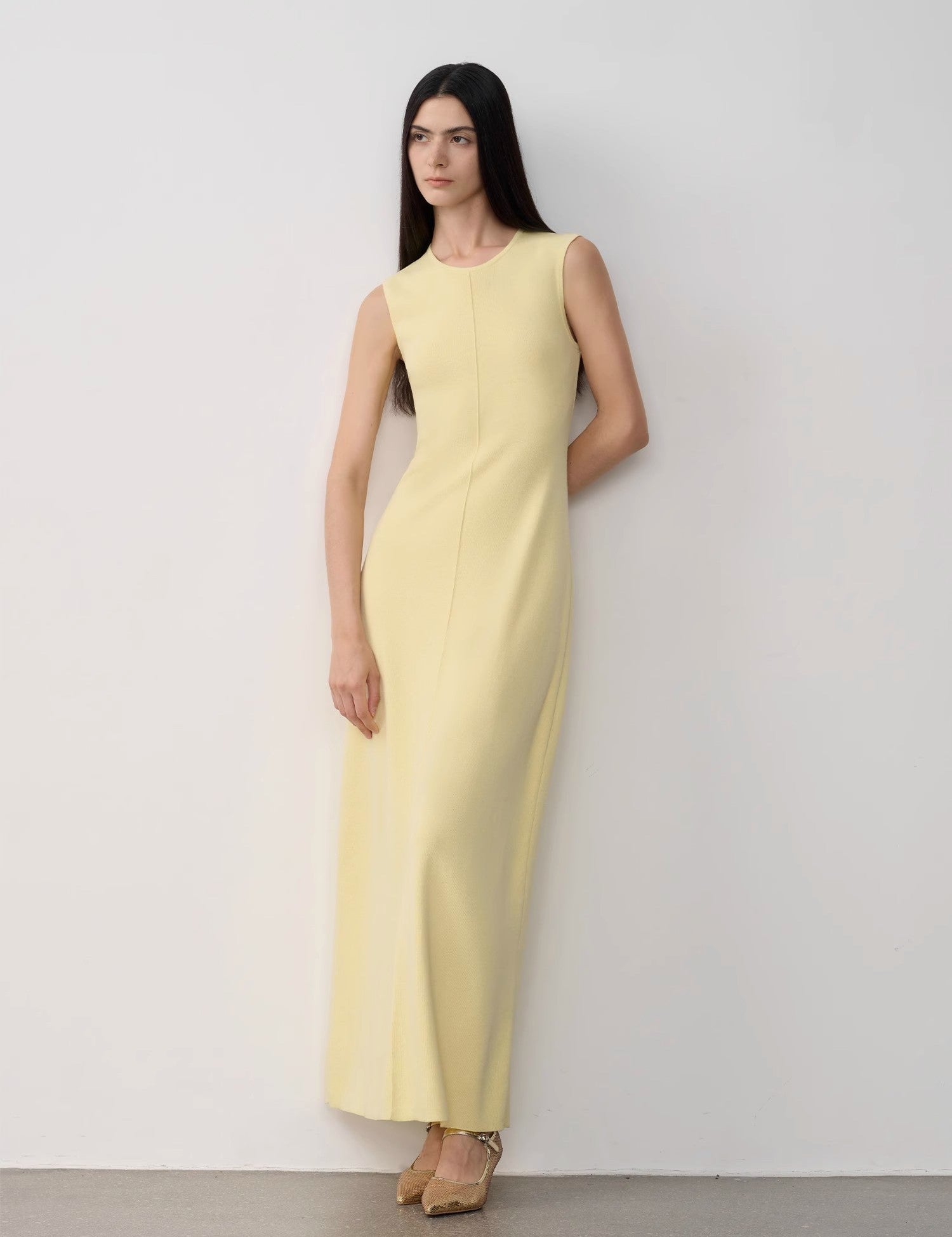 Woman wearing Solenne Merino Wool Maxi Knit Dress in yellow, ankle-length with sleeveless design, showcasing minimalist elegance.