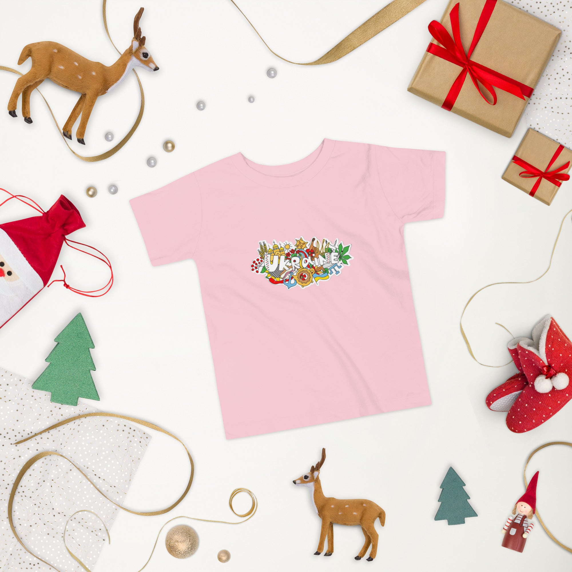Pink toddler t-shirt with Ukraine design, surrounded by festive decorations and toy reindeer, perfect for casual outings.