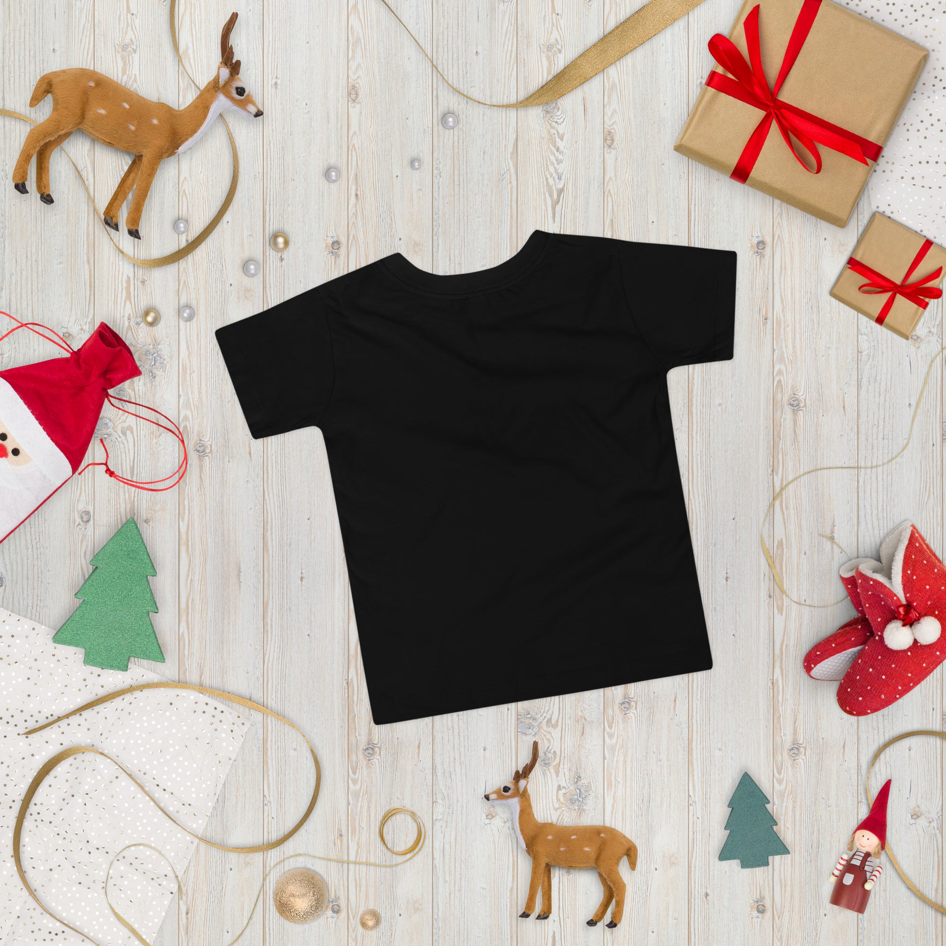 Black toddler short sleeve T-shirt with Ukraine design surrounded by holiday decorations on wooden background.