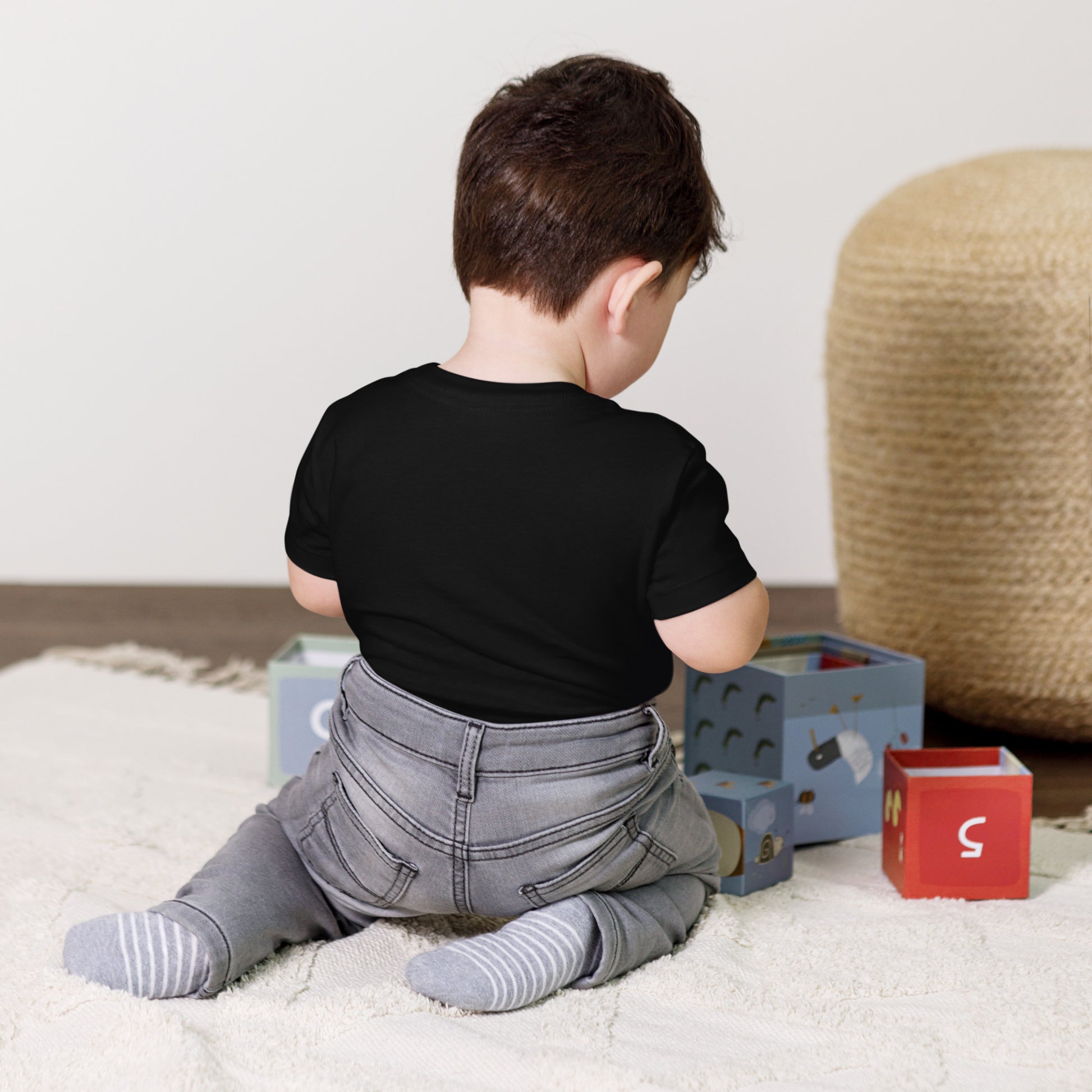 Toddler wearing Ukraine design short sleeve t-shirt while playing on a rug with colorful blocks in a cozy room.