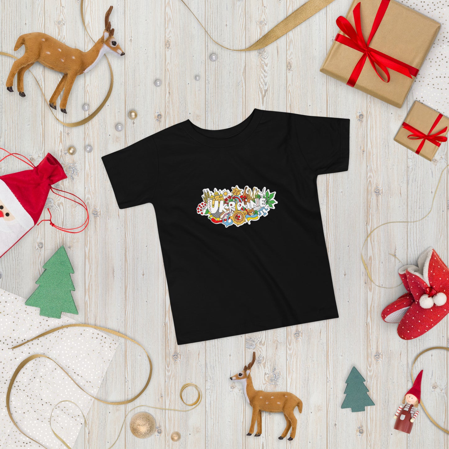 Toddler short sleeve t-shirt with Ukraine design on display, surrounded by holiday-themed decorations.