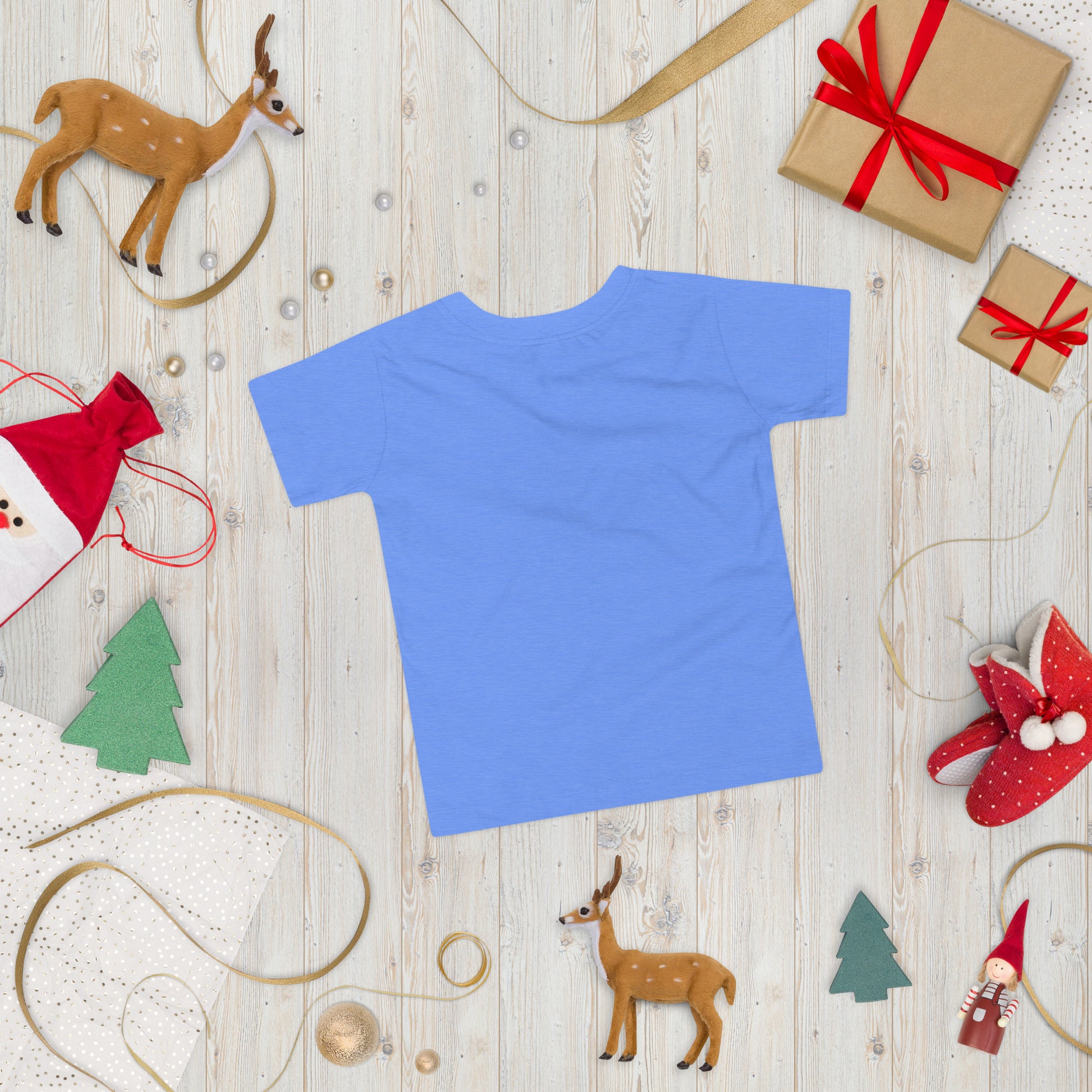 Blue toddler short sleeve T-shirt laid flat on a wooden surface, surrounded by Christmas decorations and gifts.