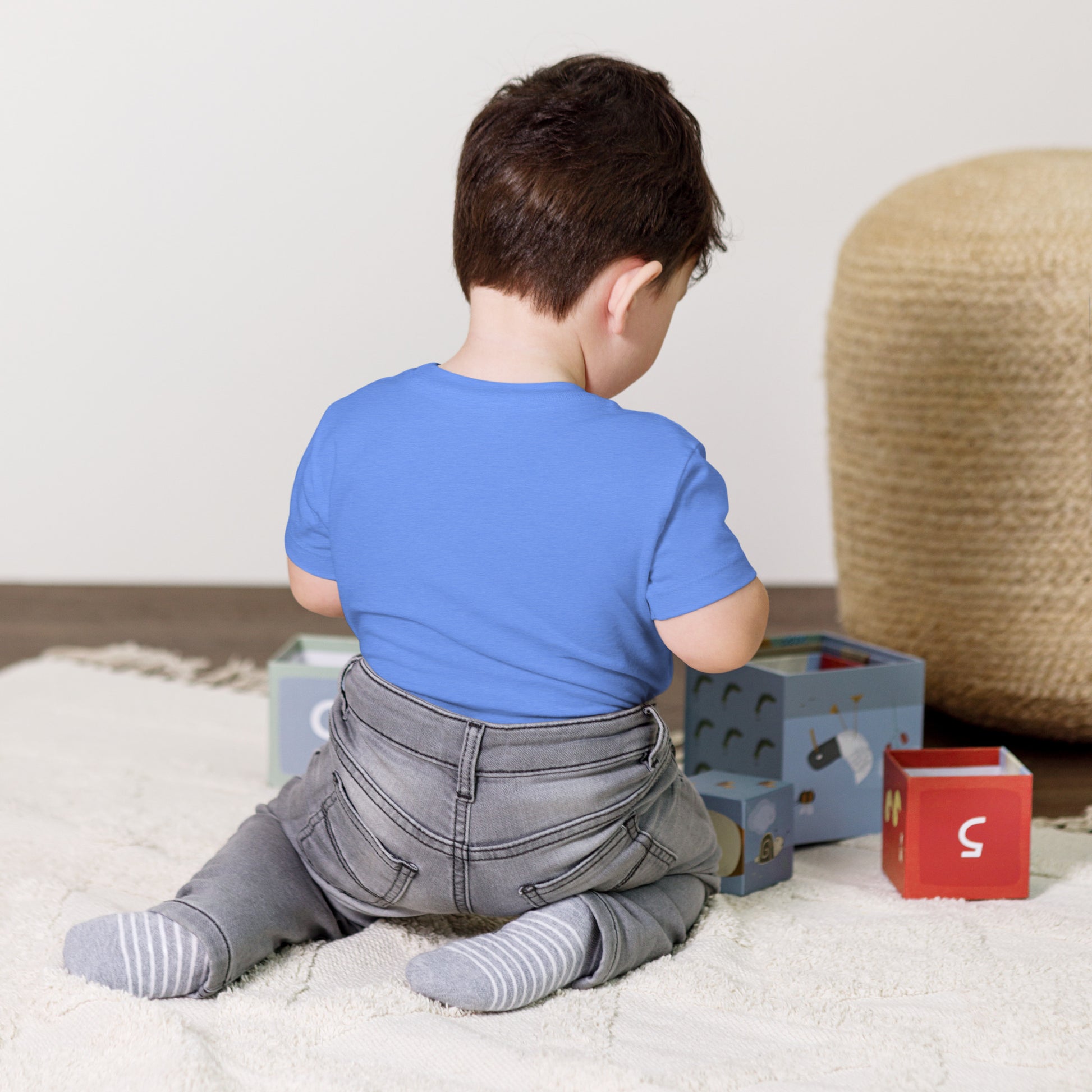 Toddler wearing Ukraine-themed short sleeve t-shirt playing with blocks on a soft rug.