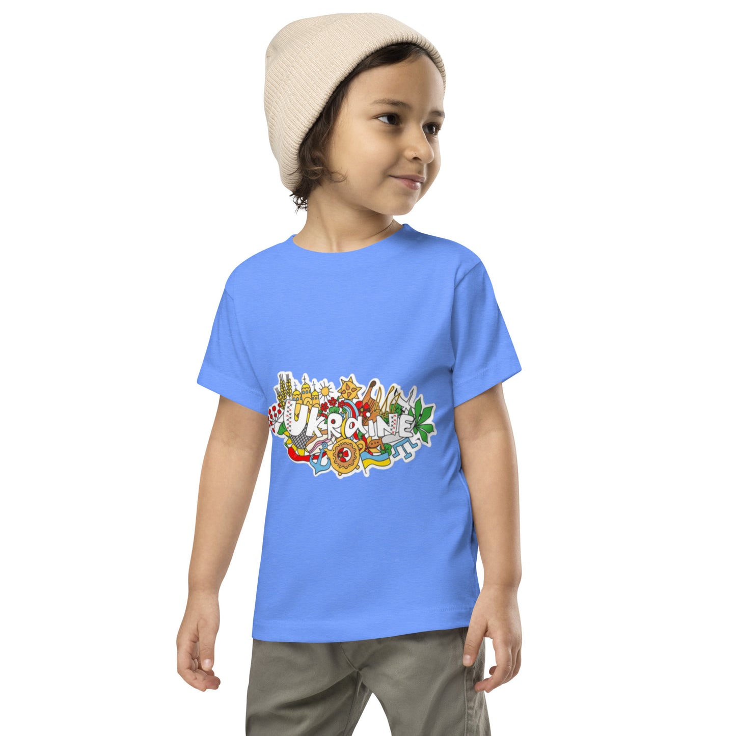 Toddler wearing blue short sleeve t-shirt with Ukraine design and a beanie, smiling confidently.