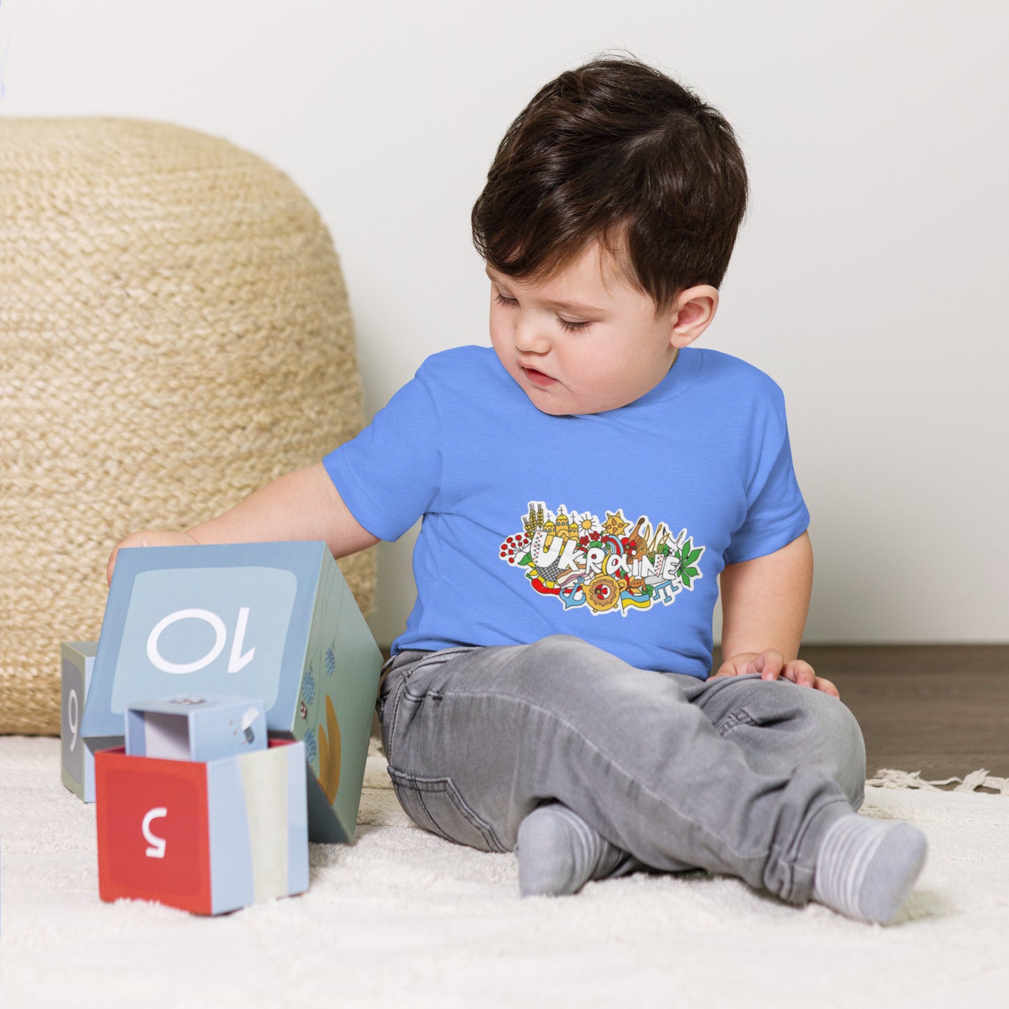 Toddler wearing Ukraine-themed short sleeve T-shirt, playing with blocks, showcasing cultural pride and comfort.