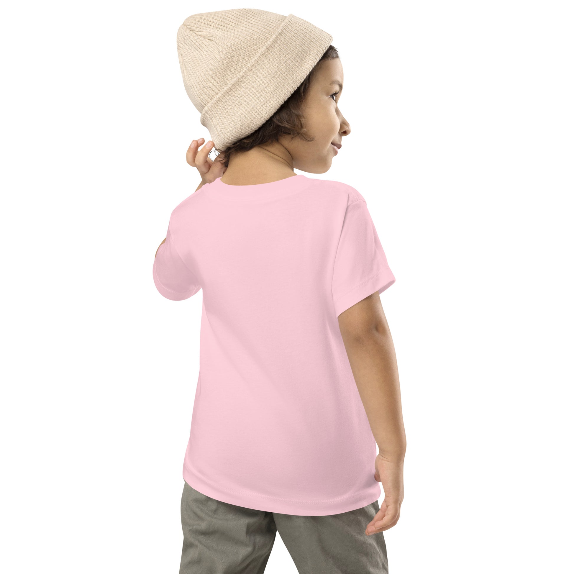 Toddler wearing pink short sleeve Ukraine design t-shirt, showcasing back view, paired with a beige beanie and grey pants.