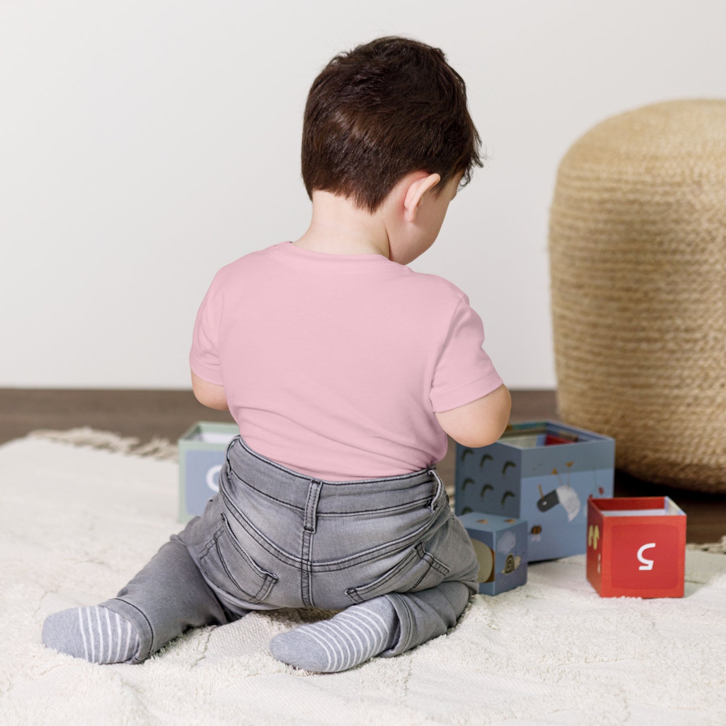 Toddler wearing a pink short sleeve T-shirt, playing with blocks on a soft rug, showcasing a Ukraine-inspired design for children's wear.